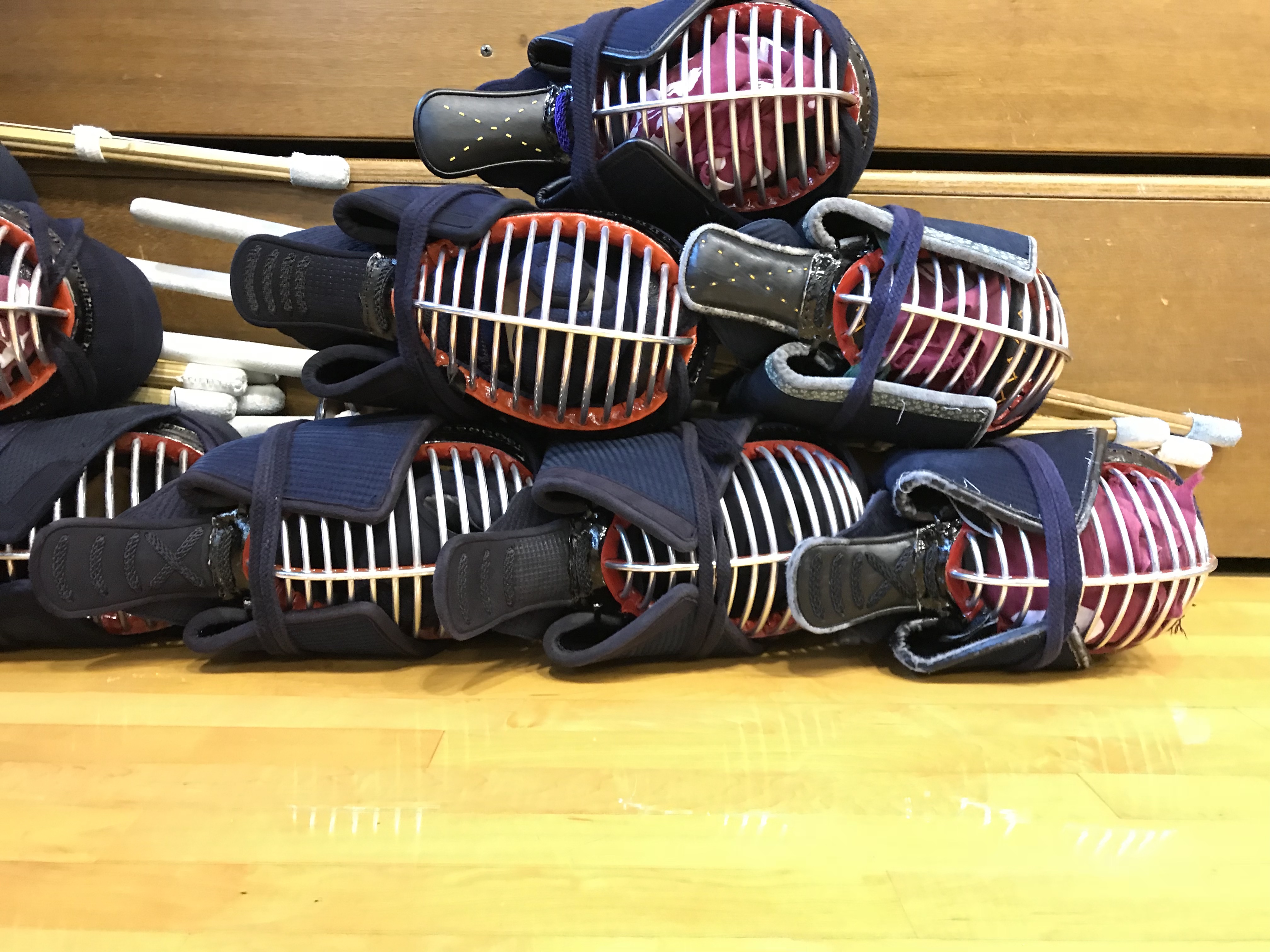 Kendo-Men und Shinai auf einem Staapel am Rand eines Dojo